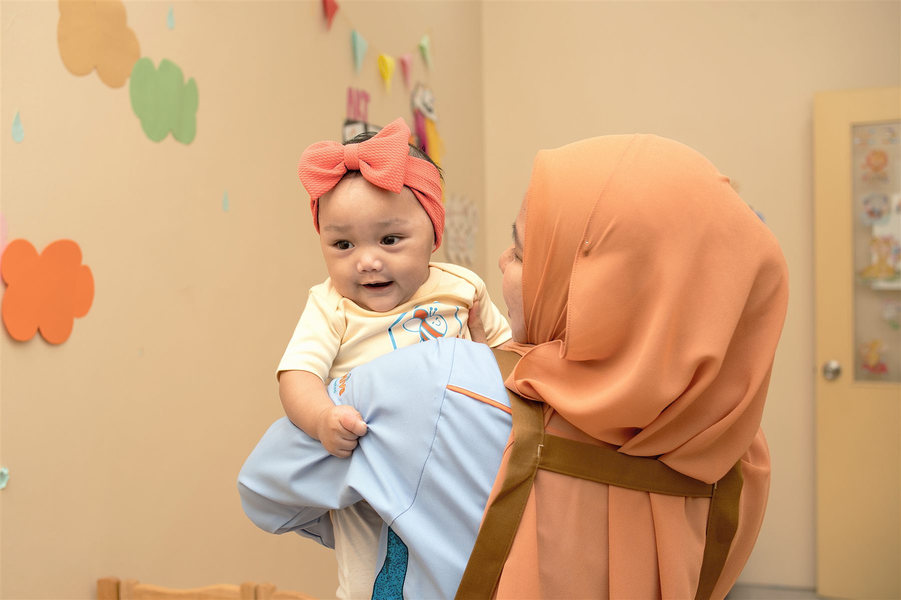 Happy Hive teacher caring for an infant in the classroom